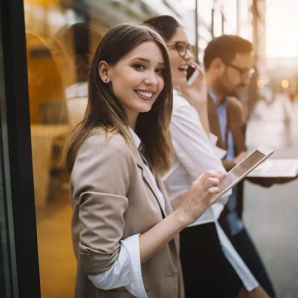 Smiling woman with tablet outdoors.