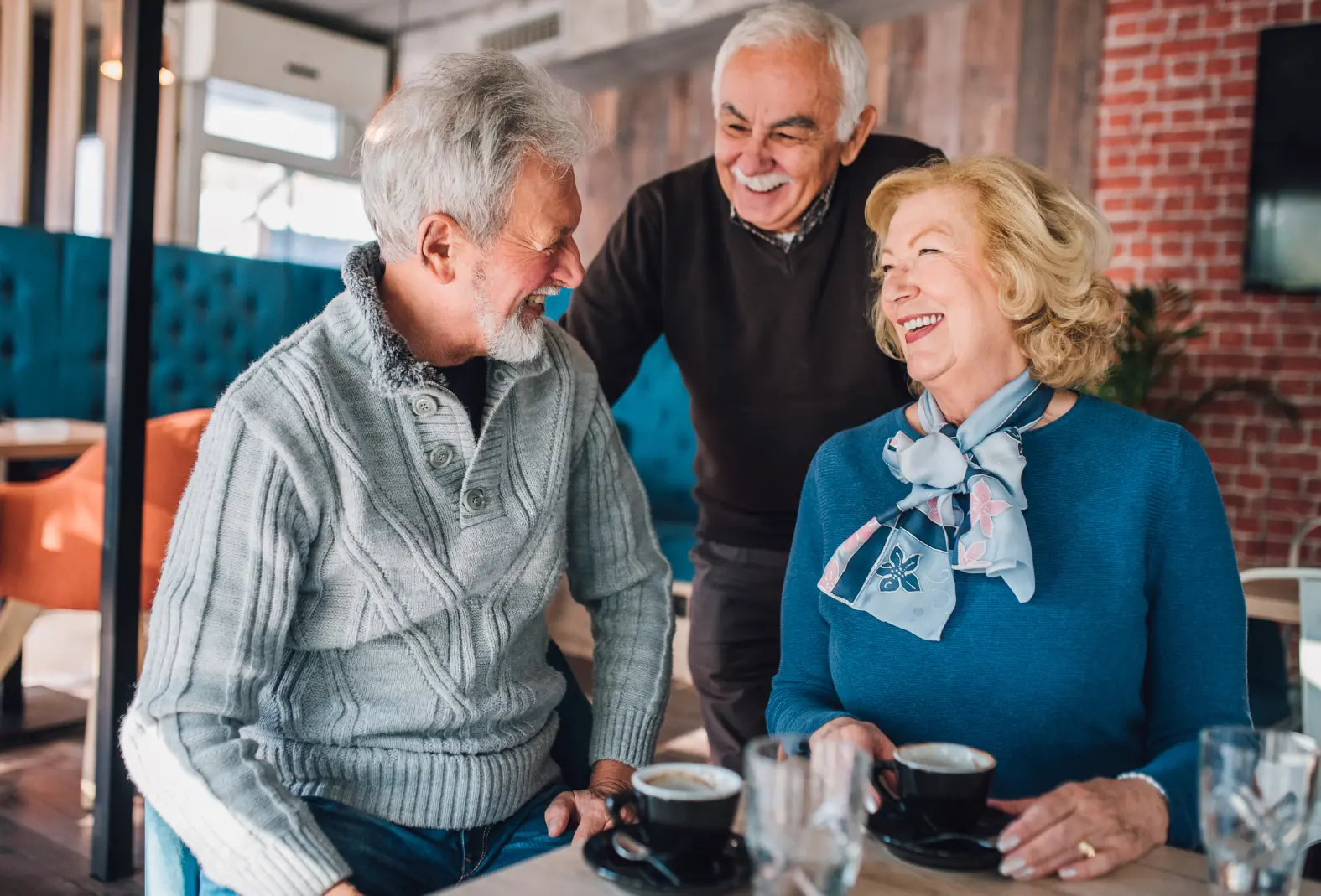 Three seniors enjoying coffee and laughter.