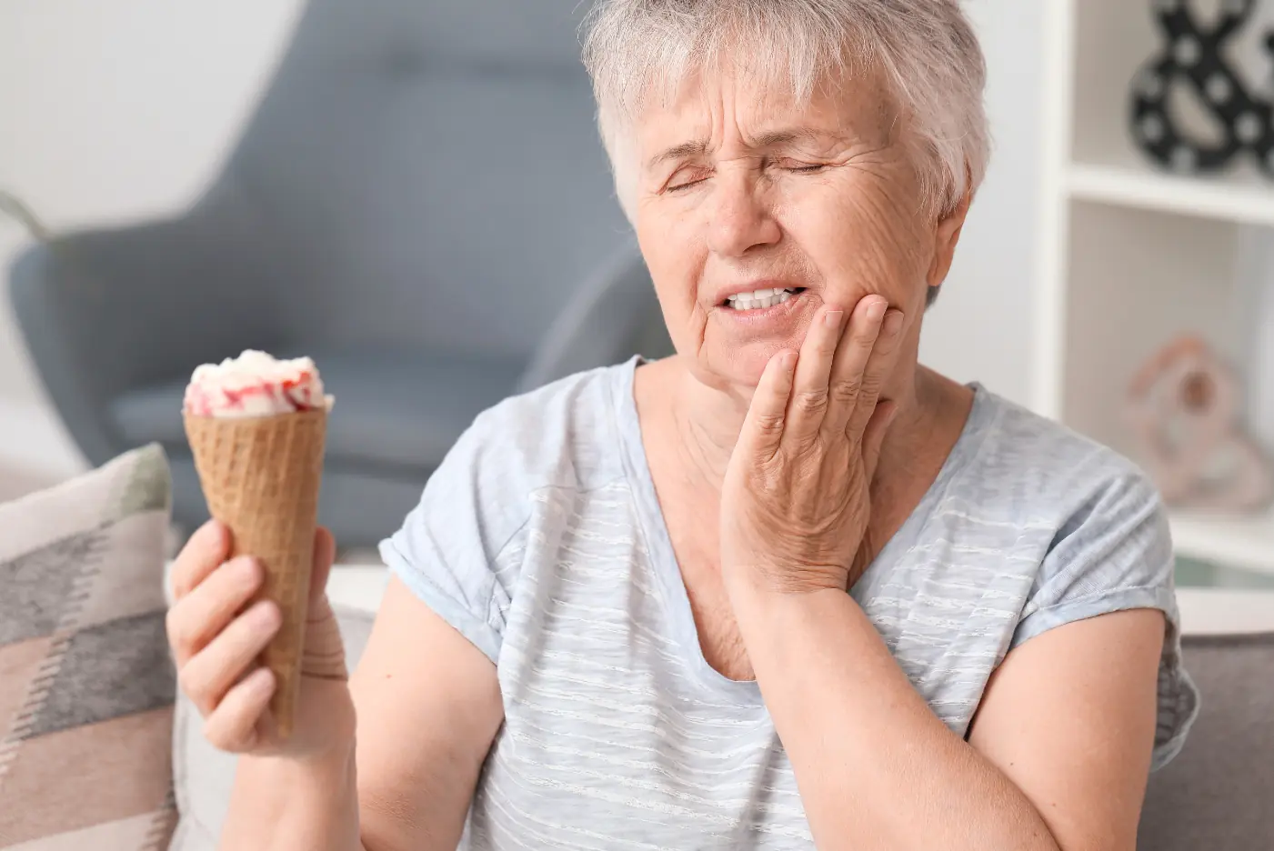 Elderly woman with ice cream, grimacing.